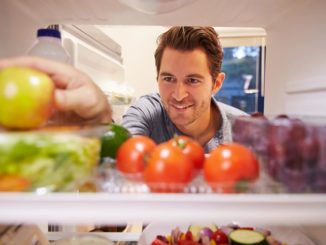 Man reaching into a refrigerator full of healthful food choices