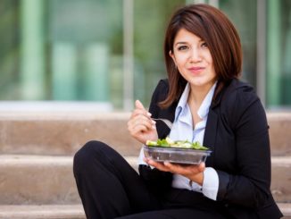Businesswoman sitting outside on steps eating a salad for lunch