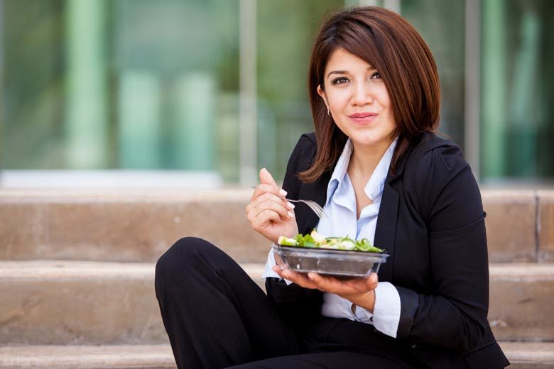Businesswoman sitting outside on steps eating a salad for lunch