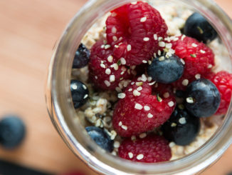 Cardamom Overnight Oats in glass jar on countertop with raspberries and blueberries