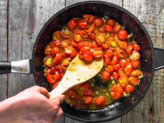 Person cooking dish with fried tomatoes, sauce for pasta, healthy food, italian meal preparing, detailed view of hands and pan, overhead