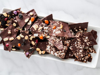 Dark chocolate bark on a white plate with a marble countertop background