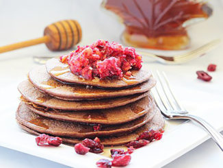 A stack of Dark Chocolate Cranberry Protein Pancakes with fresh raspberries on top