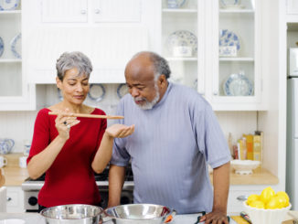 Older couple cooking and tasting dishes together in a kitchen