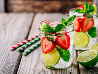 Detox water with strawberry, lime and mint. Ice cold summer cocktail or lemonade in glass mason jar