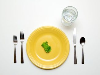 A place setting with a single piece of lettuce on the plate.