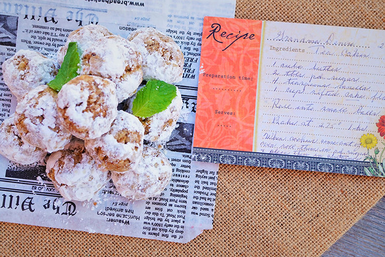 Snowball cookies set on old newspaper clipping with handwritten recipe card nearby