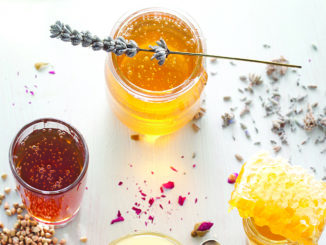 Honey variety with bee's comb in a glass jars with flowers and fresh herbs.