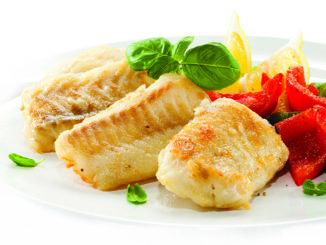 Fish filet served with vegetables on white plate