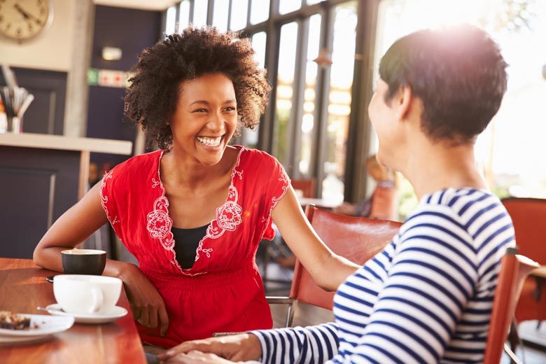 Two women meeting over coffee and laughing