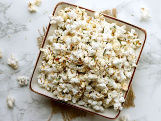Miso Butter Popcorn in a square bowl on marble background; pieces of popcorn scattered around