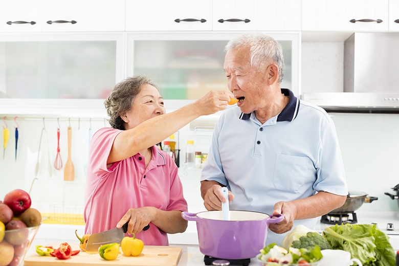 happy senior couple cooking in kitchen
