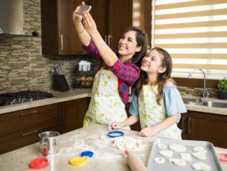 Mom and daughter in kitchen taking selfie and baking