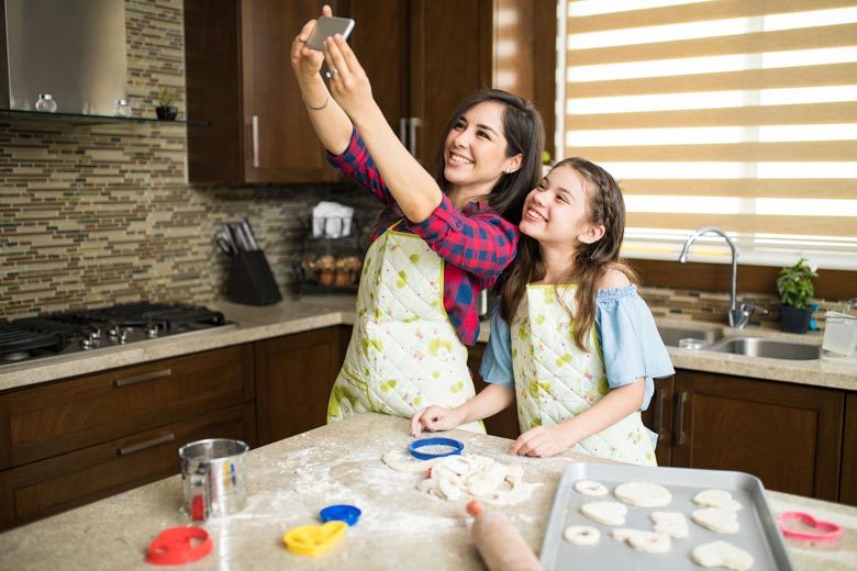 Mom and daughter in kitchen taking selfie and baking