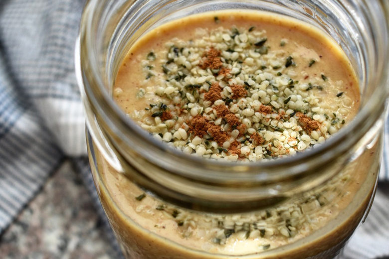A Mason jar filled with a pumpkin fig smoothie, topped with hemp hearts.