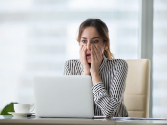 Shocked young woman looking at laptop screen. Frightened businesswoman