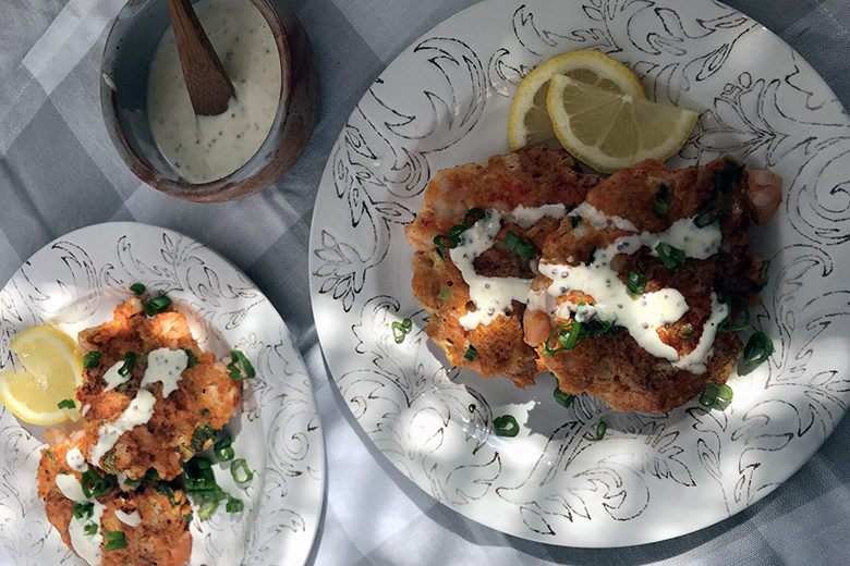 Spicy Shrimp Cakes with Creamy Yogurt Dressing served on two plates dappled with sunshine
