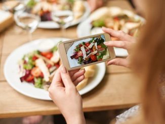 A close up of a woman's hands taking a picture of her meal, a salad