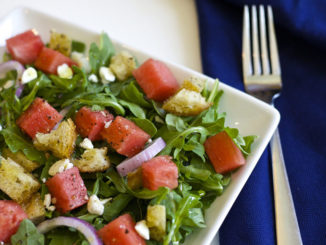 Watermelon panzanella salad in a square bowl with a fork