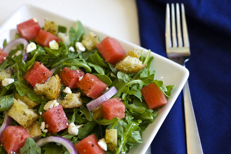 Watermelon panzanella salad in a square bowl with a fork
