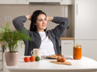 Young woman stretching during breakfast time at home